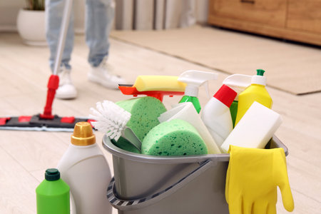 Different cleaning supplies in bucket and woman mopping floor, selective focusの写真素材