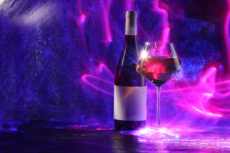 White wine in glass and bottle in neon lights, space for textの写真素材