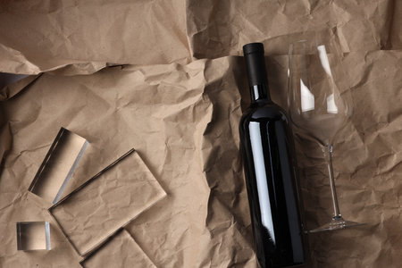 Stylish presentation of delicious red wine in bottle and glass on paper background, top view. Space for textの写真素材