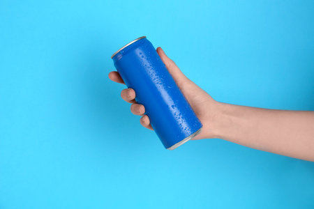 Woman with energy drink on light blue background, closeupの写真素材