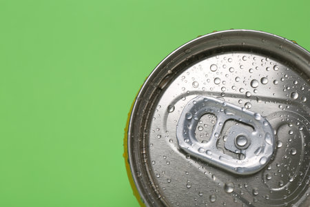 Energy drink in wet can on green background, top view. Space for text