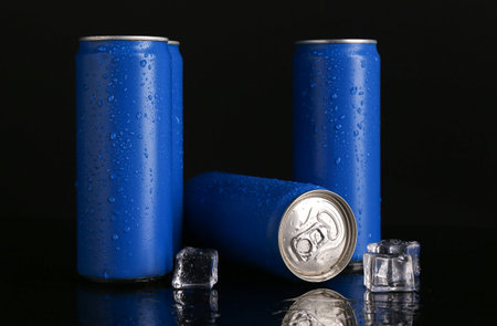 Energy drinks in wet cans and ice cubes on black backgroundの写真素材