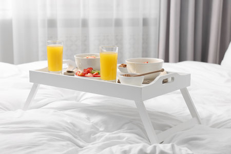 Tray with tasty breakfast on bed at homeの写真素材