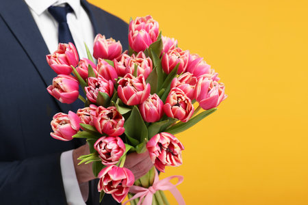 Man with beautiful bouquet on orange background, closeupの写真素材