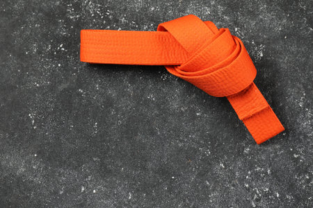 Orange karate belt on gray textured background, top view. Space for textの写真素材