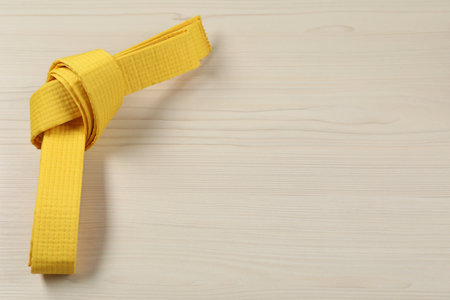 Yellow karate belt on wooden background, space for textの写真素材
