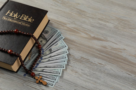 Holy Bible, cross and money on wooden table, closeup. Space for textの写真素材