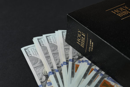 Holy Bible with money on black background, closeupの写真素材