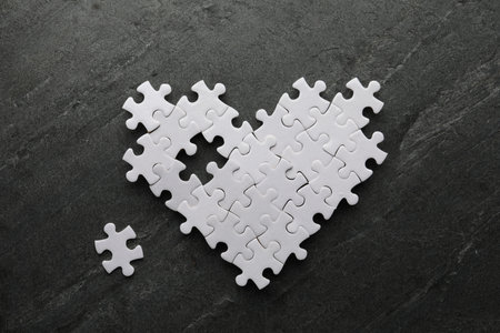 Heart made of puzzles with missing piece on black tableの写真素材