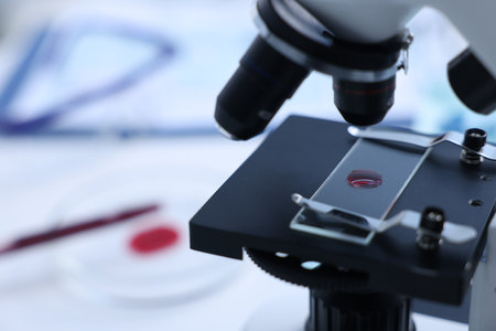 Modern medical microscope with sample of red liquid in laboratory, closeup. Space for textの写真素材
