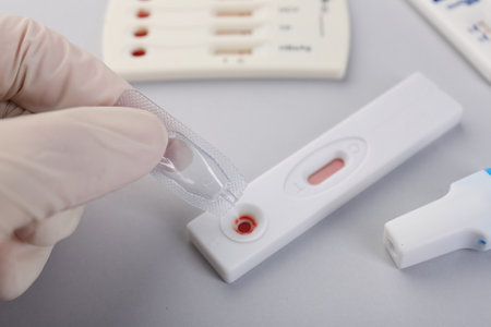 Doctor dropping buffer solution onto disposable express test cassette on light background, closeup