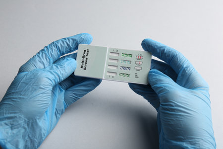 Doctor holding multi-drug screen test on light gray background, closeupの写真素材