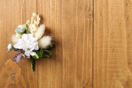 Stylish boutonniere on wooden table, top view. Space for text