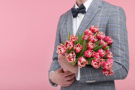 Man with beautiful bouquet on pink background, closeup. Space for textの写真素材