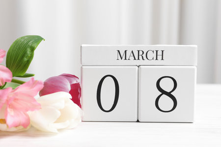 International Women's day - 8th of March. Wooden block calendar and beautiful flowers on white tableの写真素材