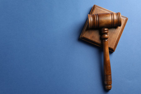 Wooden gavel and sound block on blue table, top view. Space for textの写真素材