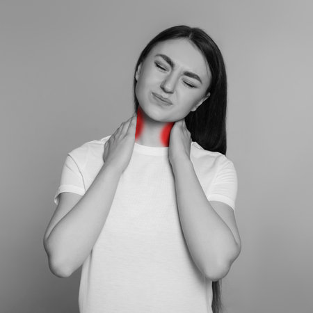 Woman suffering from rheumatism on light background. Black and white effect with red accent in painful areaの写真素材