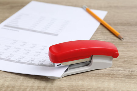 Bright stapler with documents on wooden table, closeupの写真素材