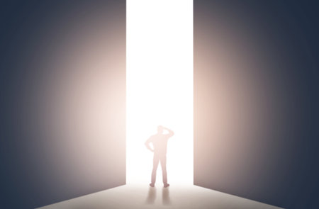 Silhouette of man standing in front of light hole, back viewの写真素材