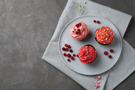 Delicious cupcakes with pink cream and berries on gray table, top view. Space for textの写真素材