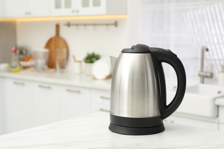 Modern electric kettle on table in kitchen. Space for textの写真素材