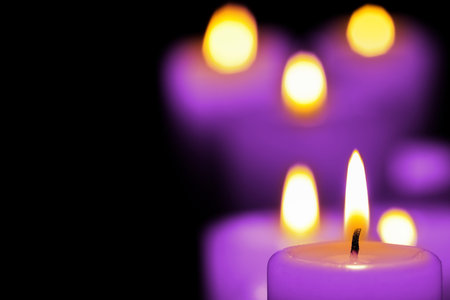 Burning violet candle on black background, closeup. Funeral attributesの写真素材