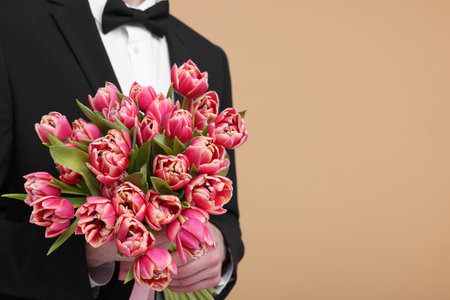 Man with beautiful bouquet on beige background, closeup. Space for textの写真素材
