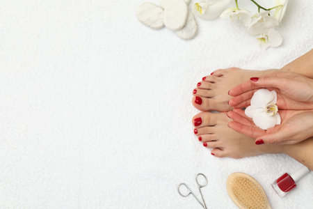 Woman with stylish red toenails after pedicure procedure and orchid flowers on white terry towel, top view. Space for textの写真素材