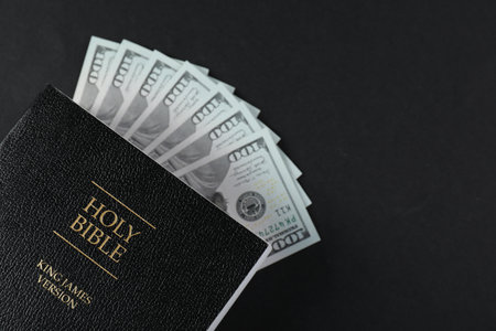 Holy Bible with money on black background, top view. Space for textの写真素材
