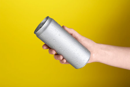 Woman with energy drink on yellow background, closeupの写真素材