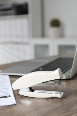 Stapler on wooden table indoors, closeup view