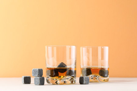 Whiskey stones and drink in glasses on light tableの写真素材