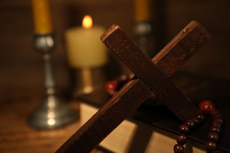 Wooden cross, Bible, rosary beads and church candles on table, closeup. Space for textの写真素材