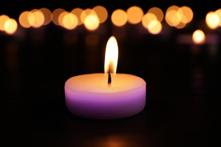 Burning violet candle on dark surface. Funeral attributesの写真素材