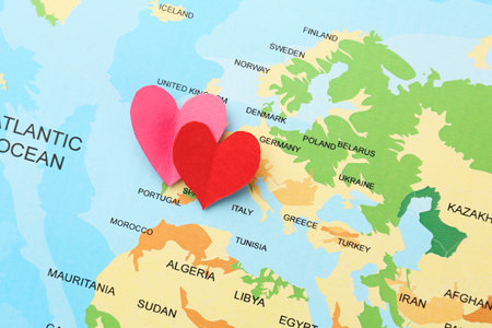 Honeymoon concept. Two red paper hearts on world map, top view