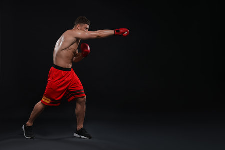 Man in boxing gloves fighting on black background. Space for textの写真素材