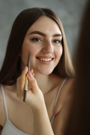 Smiling woman drawing freckles with pen indoorsの写真素材