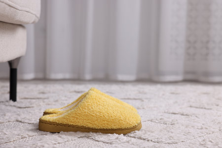 Yellow soft slippers on light carpet. Space for textの写真素材
