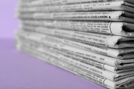 Stack of newspapers on light violet background, closeup. Journalist's workの写真素材