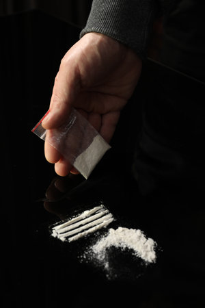 Drug addiction. Man with cocaine at black table, closeupの写真素材