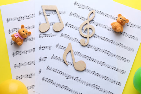 Baby songs. Music sheets, wooden notes, toy bears and balls on yellow background, top viewの写真素材