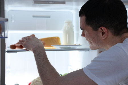 Man sausages taking out of the refrigerator at nightの写真素材