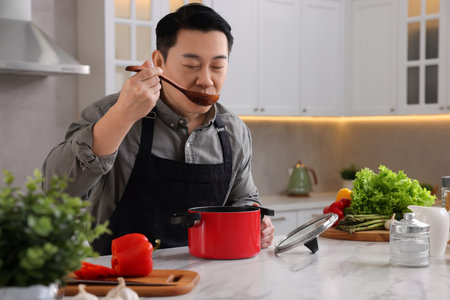 Cooking process. Man tasting dish at countertop in kitchenの写真素材