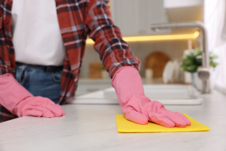 Woman cleaning white marble table with microfiber cloth in kitchen, closeupの写真素材