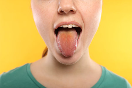 Gastrointestinal diseases. Woman showing her yellow tongue on color background, closeupの写真素材