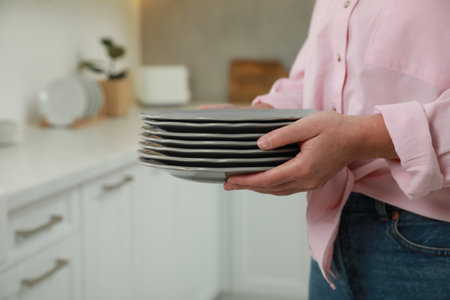 Woman holding plates in kitchen, closeup viewの写真素材