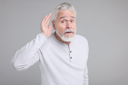 Portrait of surprised senior man on gray backgroundの写真素材