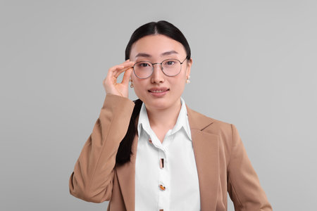 Portrait of smiling businesswoman on gray backgroundの写真素材