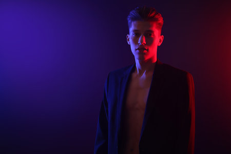 Sexy young man on dark background in neon lights. Space for textの写真素材