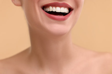 Woman with beautiful lips smiling on beige background, closeupの写真素材
